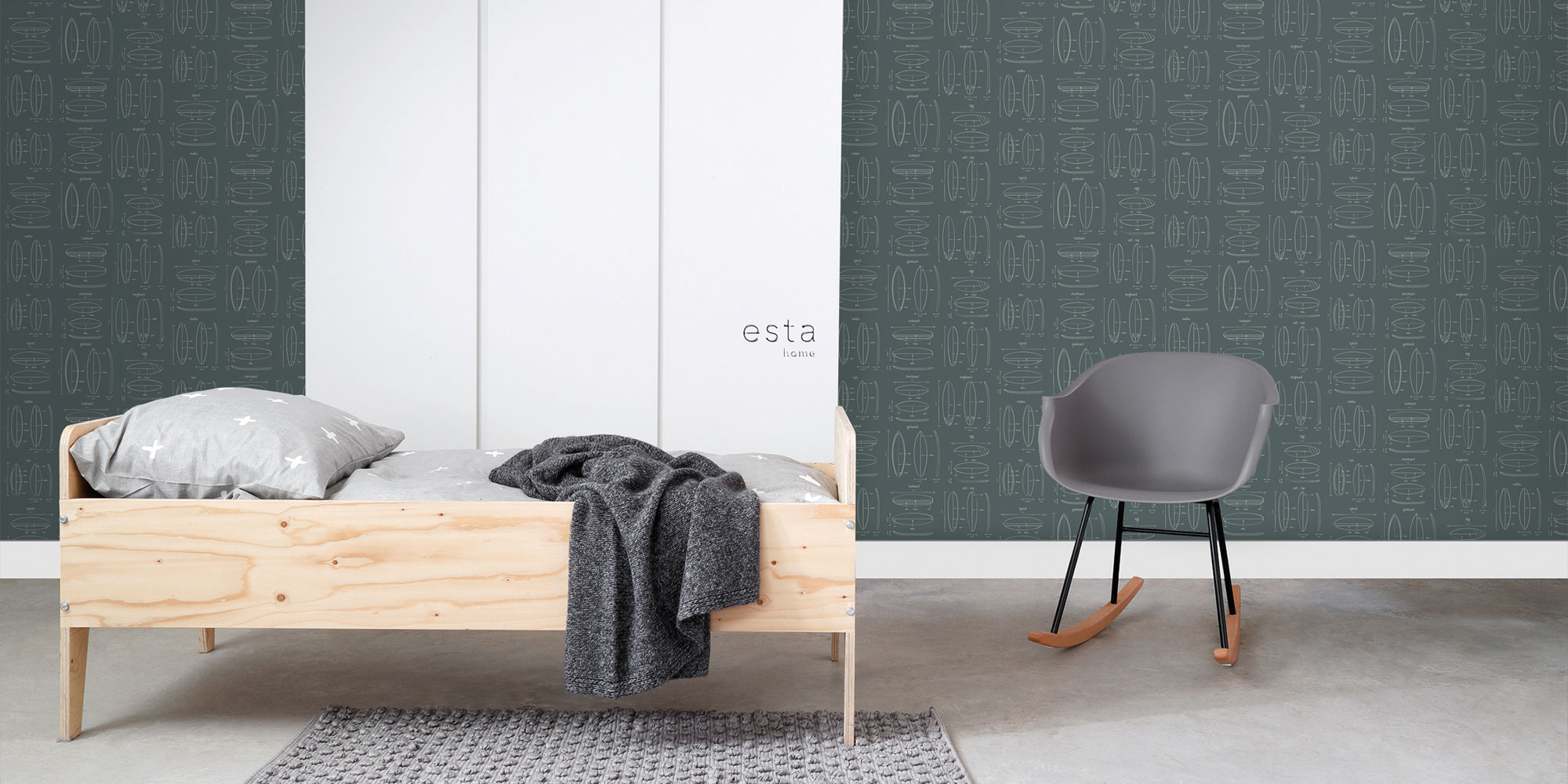 Kinderzimmer mit dunkelgrüner Kindertapete mit Surfbrett Motiven im Linien Design neben Holzbett und grauem Sessel
