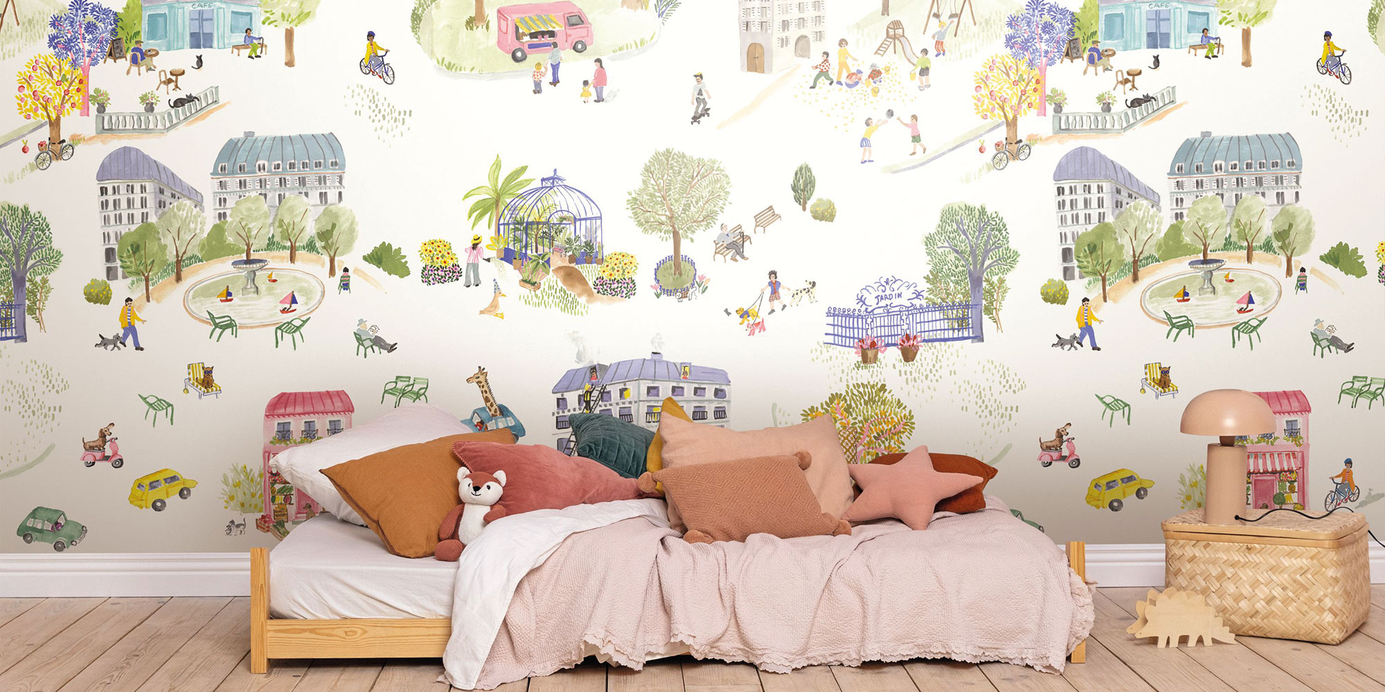 Girls room with playful childrens wallpaper showing city park scenes houses animals and people in soft colors