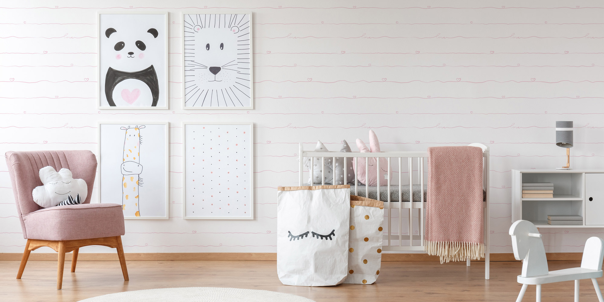 Wand im Babyzimmer mit einer weißen Kindertapete für Mädchen, verziert mit zarten rosa gewellten Linien, die eine sanfte und verspielte Atmosphäre schafft.