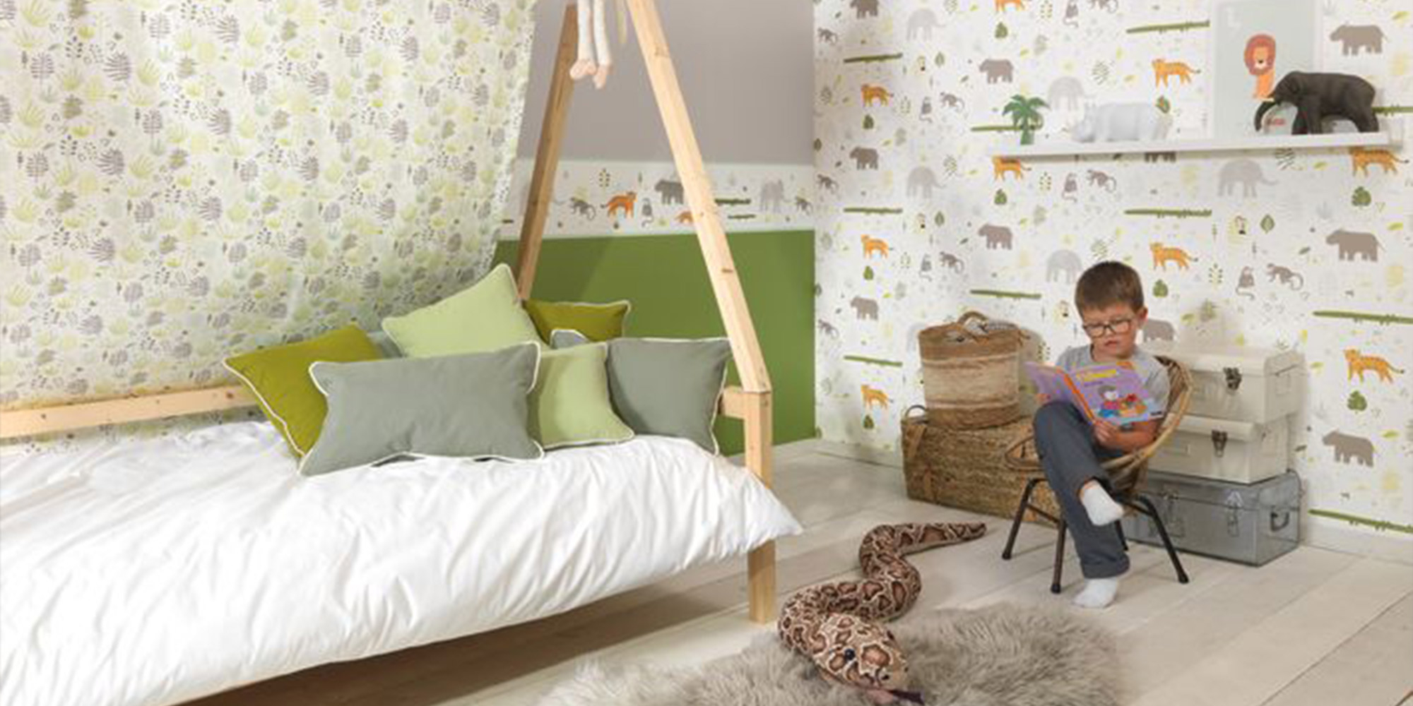 Wandgestaltung im Kinderzimmer mit einer Tiertapete und einem dazu passenden Dekostoff mit Tiermotiven.