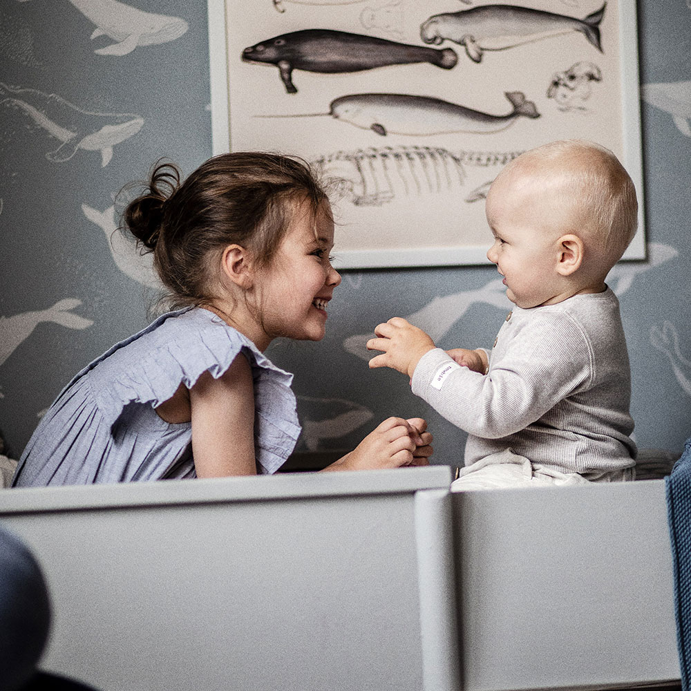 Tapeten mit besonderen Optiken Mädchen und Baby spielen vor Tapete mit Wal-Motiv