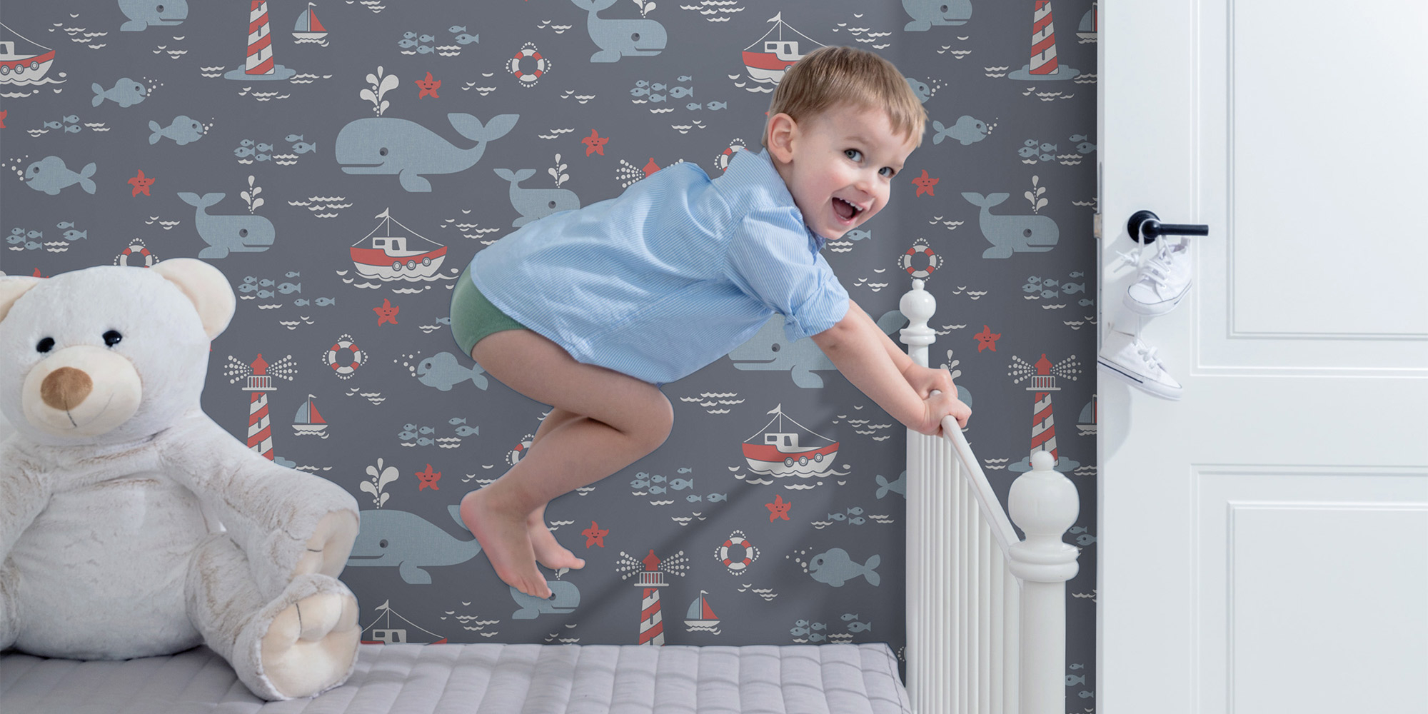 Eine blaue Tapete für das Kinderzimmer mit Walen, Booten und Leuchttürmen.