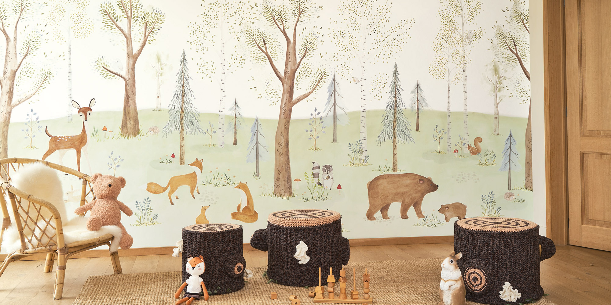 Wandgestaltung im Kinderzimmer mit einem Wandbild mit Waldmotiven, Bäumen und kleinen Waldtieren.