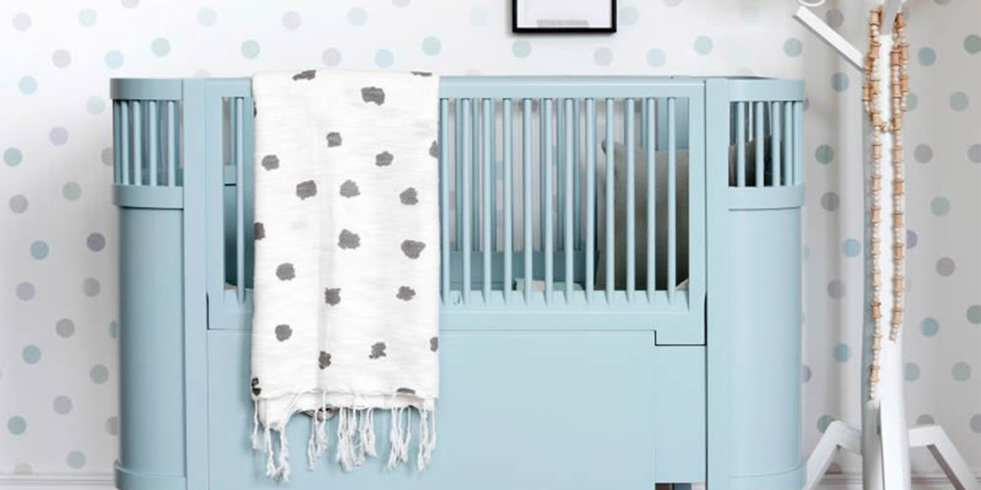 Eine weiße Punktetapete mit hellblauen großen Punkten für die Wandgestaltung im Babyzimmer.