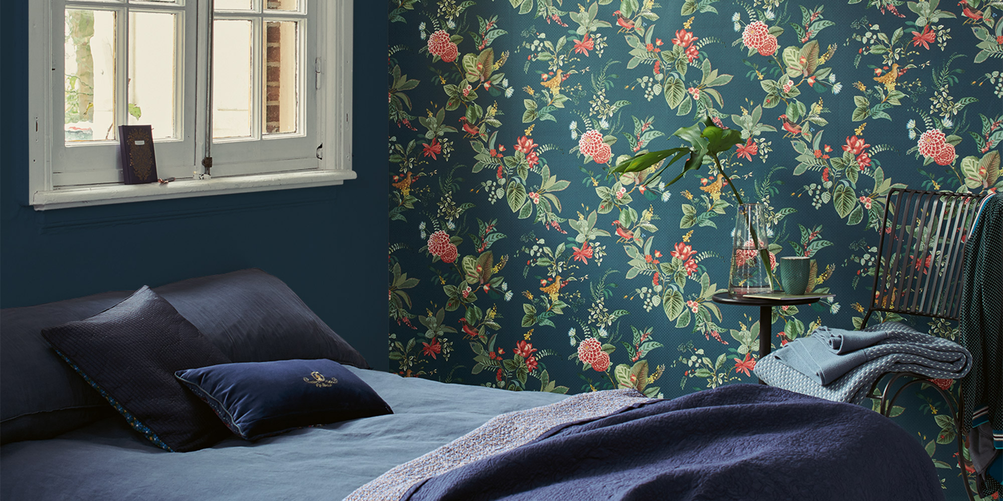 Blaues Schlafzimmer mit einer Kombination aus blauer Unitapete und passender blauer Blumentapete, die eine harmonische Atmosphäre schafft.