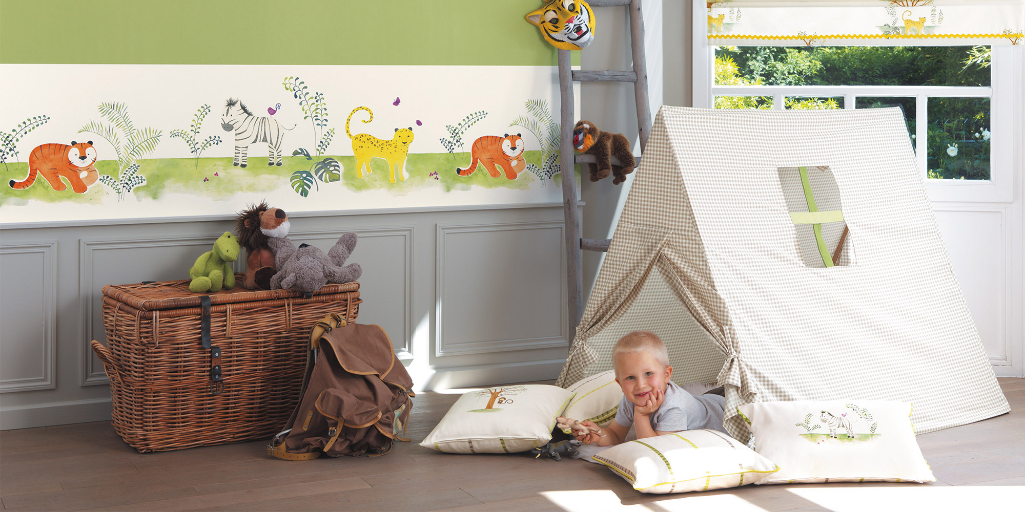 Eine breite Bordüre mit Tieren in Kombination mit einer grünen Unitapete im Jungenzimmer.