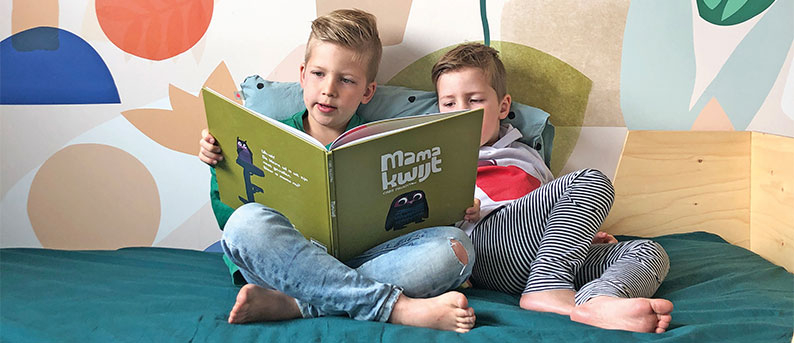 Kreative Kinderzimmerideen mit Tapeten Kinder mit Buch vor farbenfroher Wandgestaltung
