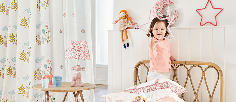 Ideen und Fakten rund ums Kind und Wohnen Mädchen im rosa Kinderzimmer mit verspielter Deko und Blumentapete