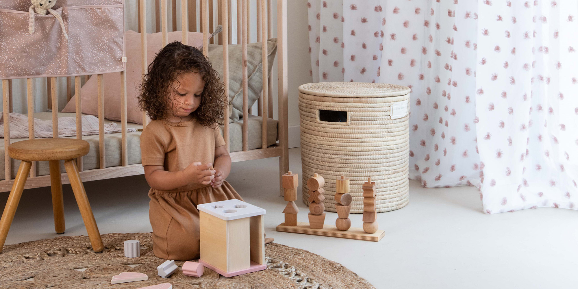 Eine Gardine im Mädchenzimmer aus einem weißen Dekostoff mit grauen aufgenähten Pompoms.