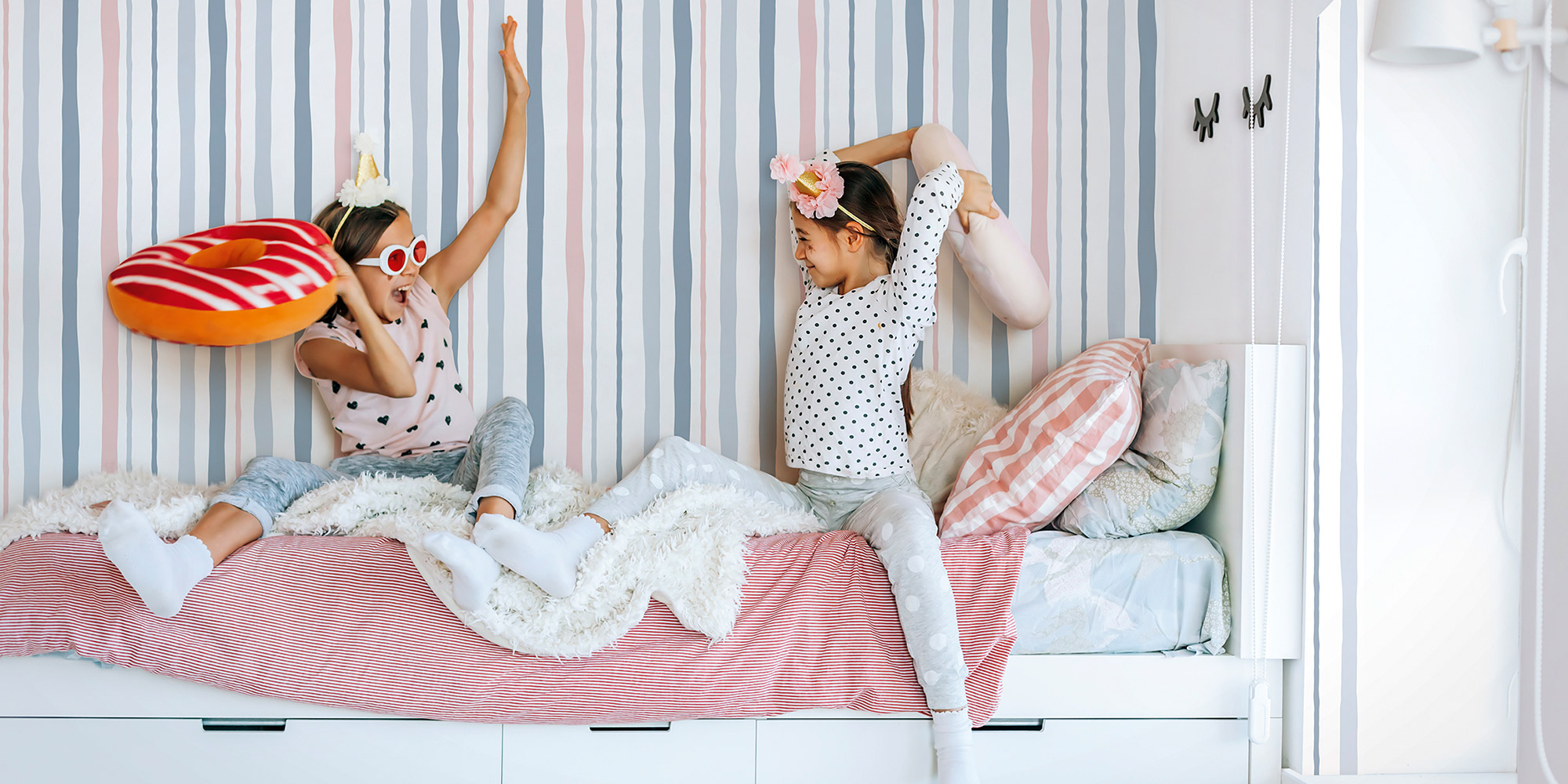 Eine Streifentapete in weiß, blau und rosa für die Wände im Mädchenzimmer.