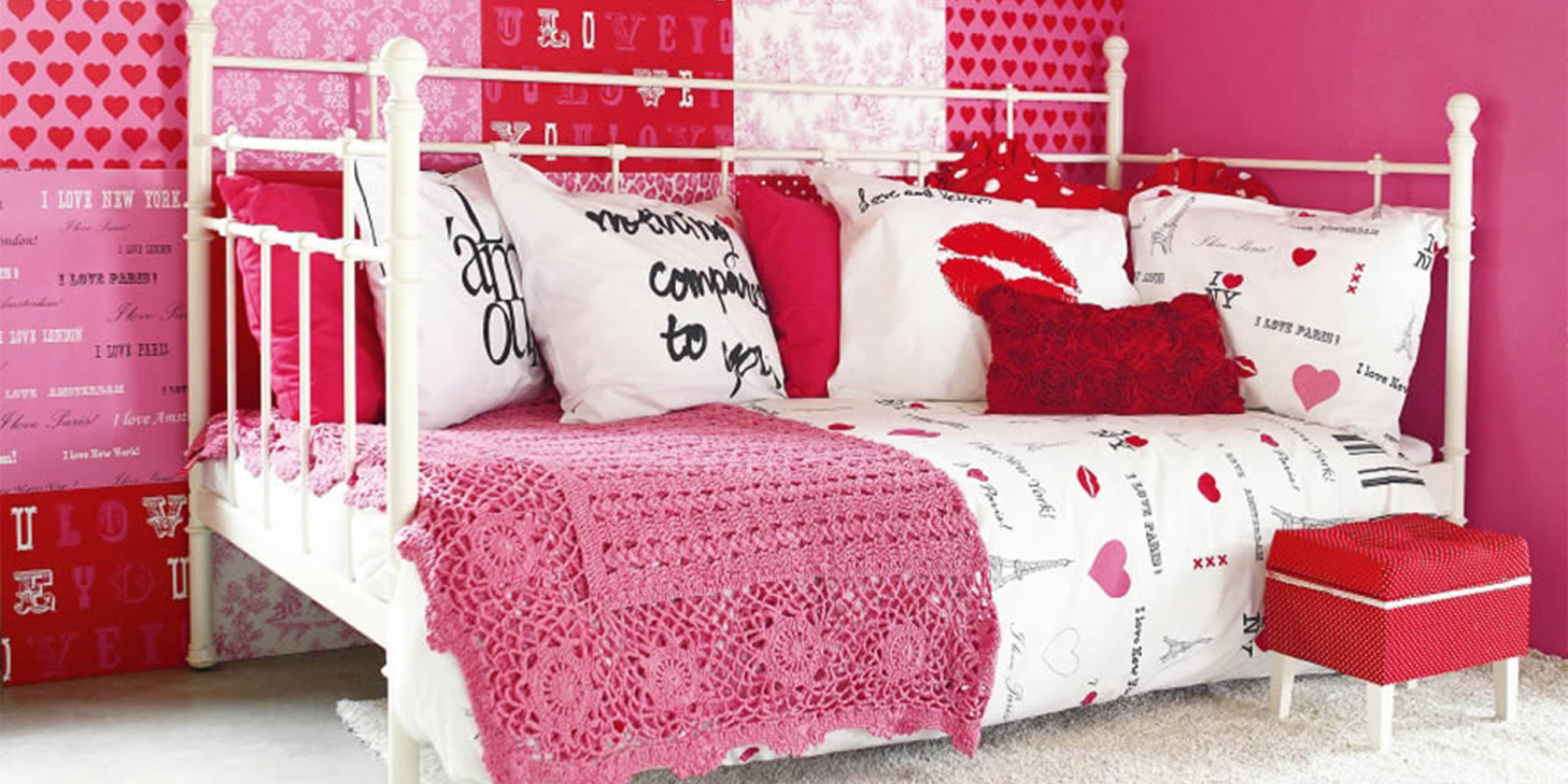 Pink gestaltetes Mädchenzimmer mit einer Wand aus unterschiedlichen, harmonisch kombinierten Tapeten mit Herzen, Buchstaben und floralen Ornamenten.