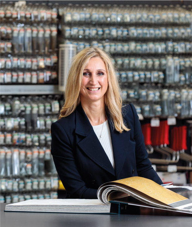 Nicole Ewering im Fachmarkt. Ewering Geschäftsführerin Nicole Ewering im Fachmarkt vor einer Auswahl Tapetenbücher.