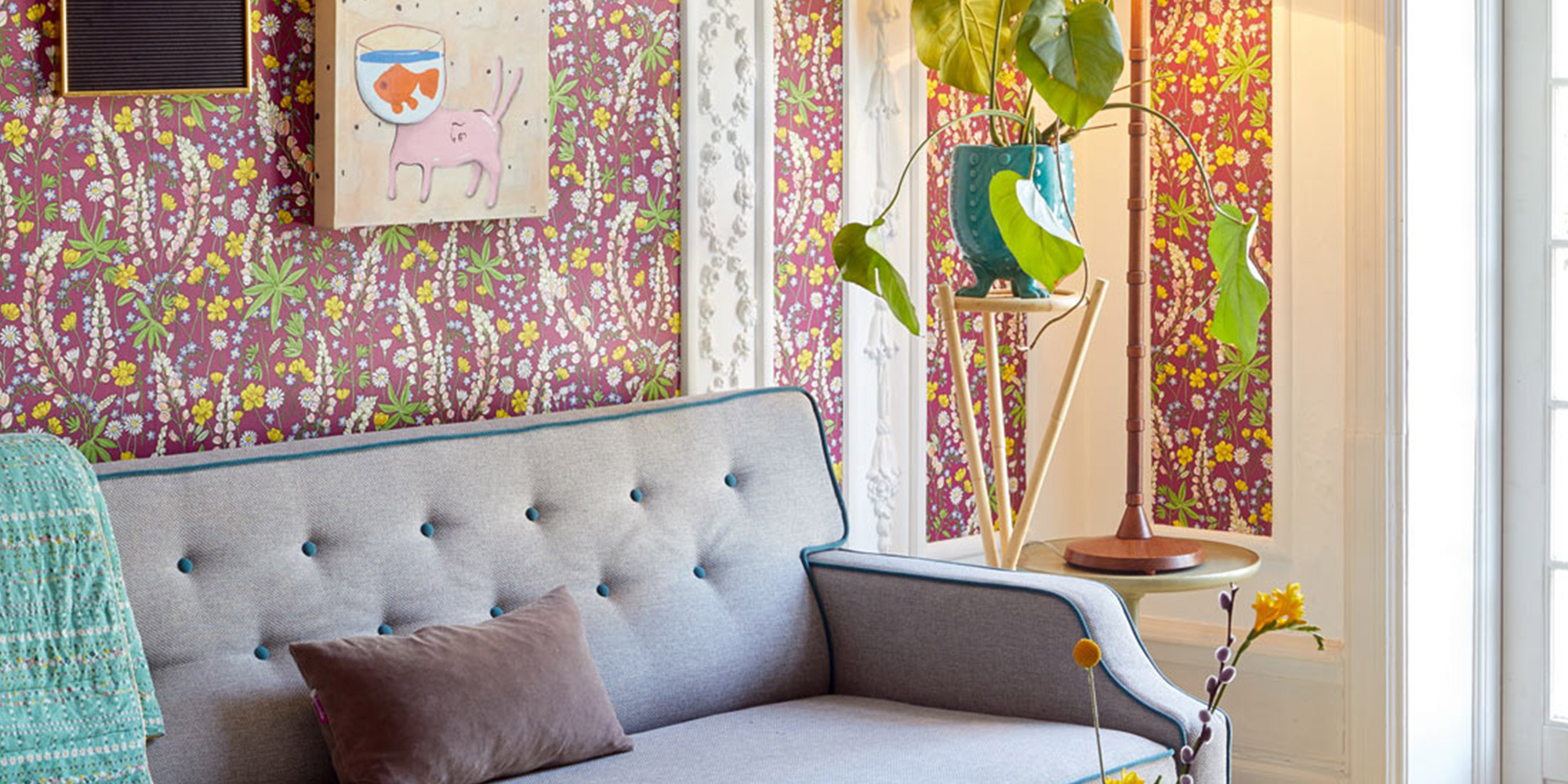 Mädchenzimmer mit einer Wand hinter dem Sofa, gestaltet mit einer lilafarbenen Blumentapete für eine elegante und verspielte Atmosphäre.