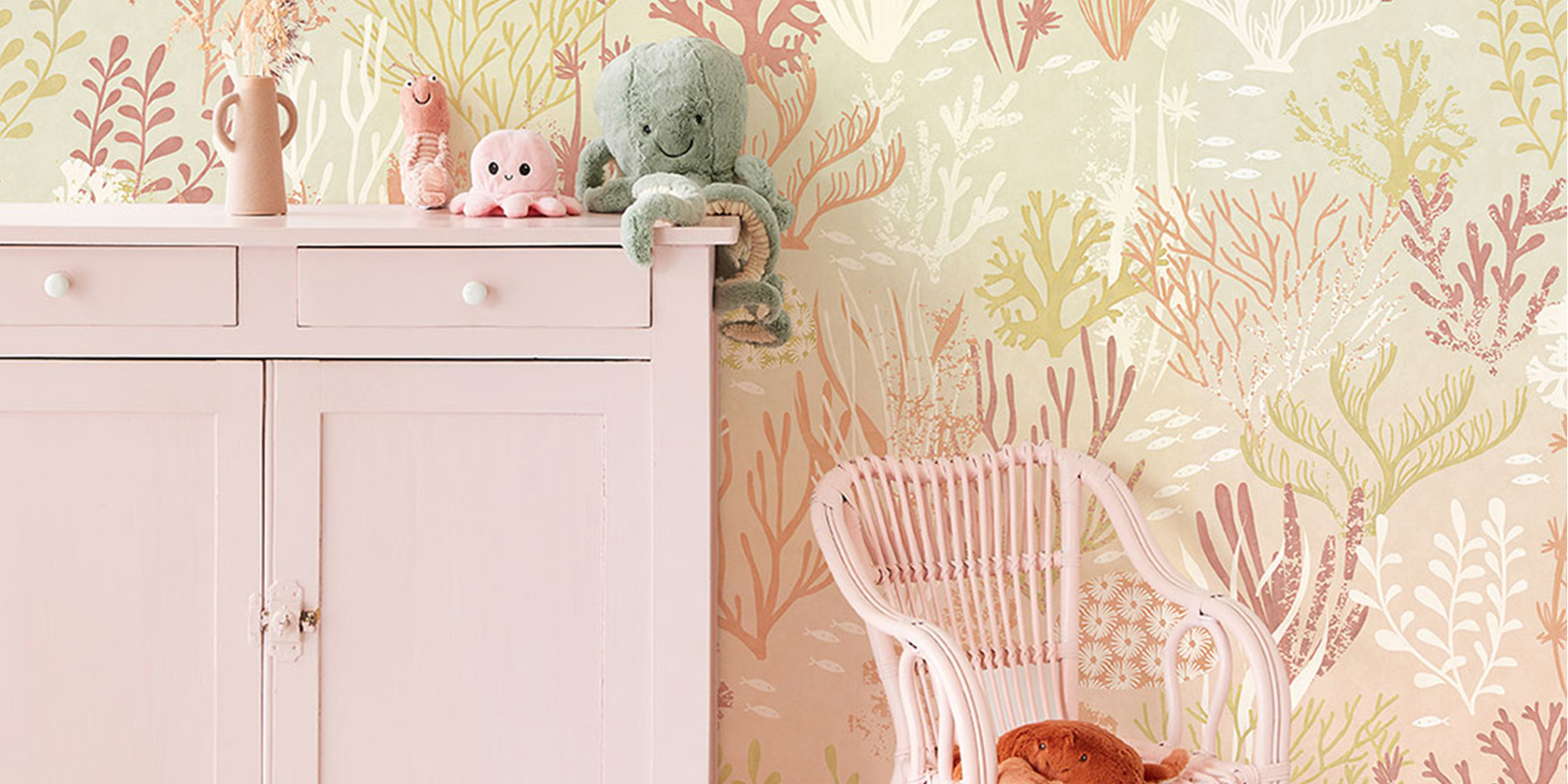 Kinderzimmer mit einer pastellfarbenen Vliestapete mit Unterwasser-Korallenmotiven, harmonisch abgestimmt auf rosafarbene Kinderzimmermöbel.