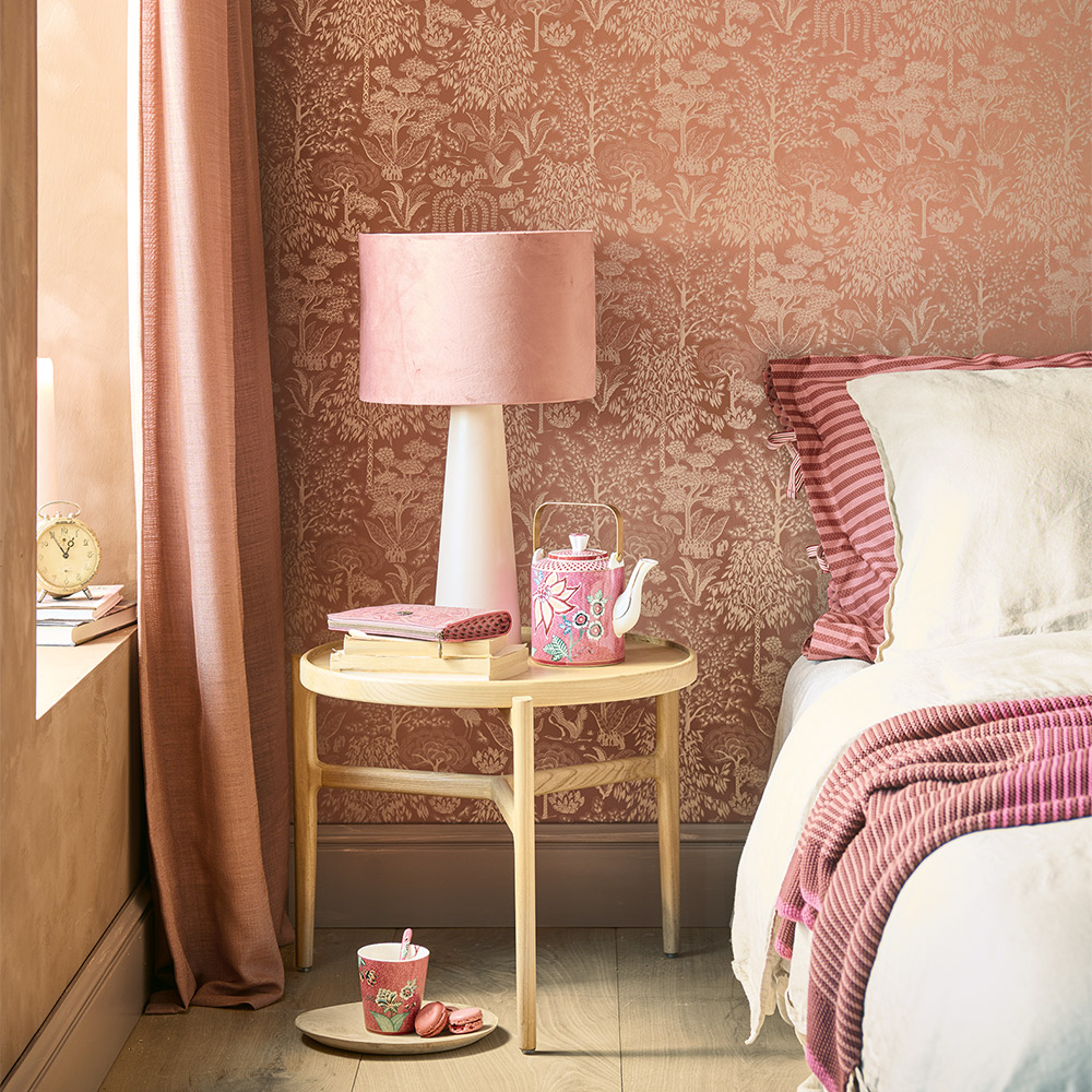 Stilvolles Schlafzimmer mit einer eleganten, roséfarbenen Tapete mit floralen Mustern. Eine gemütliche Nachttisch-Lampe und abgestimmte Textilien sorgen für ein harmonisches Ambiente.