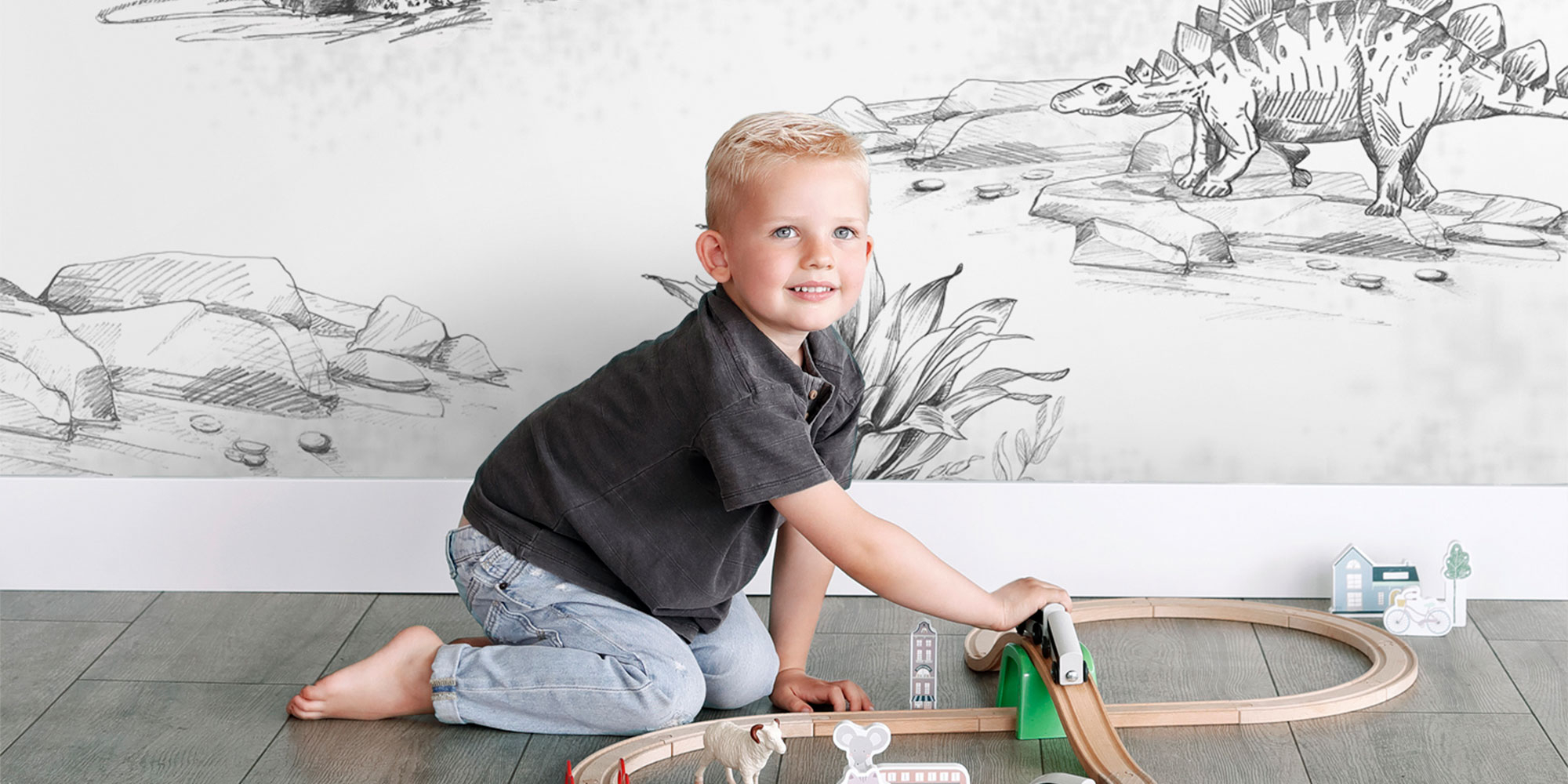 White kids room with black and white dinosaur mural and wooden toys
