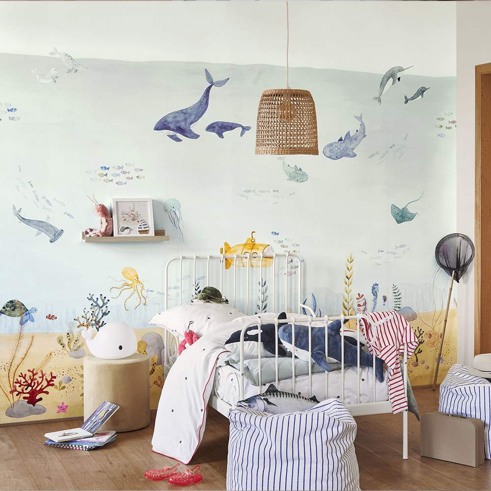 Mit diesem Wandbild zum Thema Unterwasserwelt wird die Wand hinter dem Kinderbett hervorgehoben. Eine bunte Unterwasserwelt mit U-Booten, Walen, Fischen und Korallen verschönert in diesem Kinderzimmer die Wand hinter dem Bett.