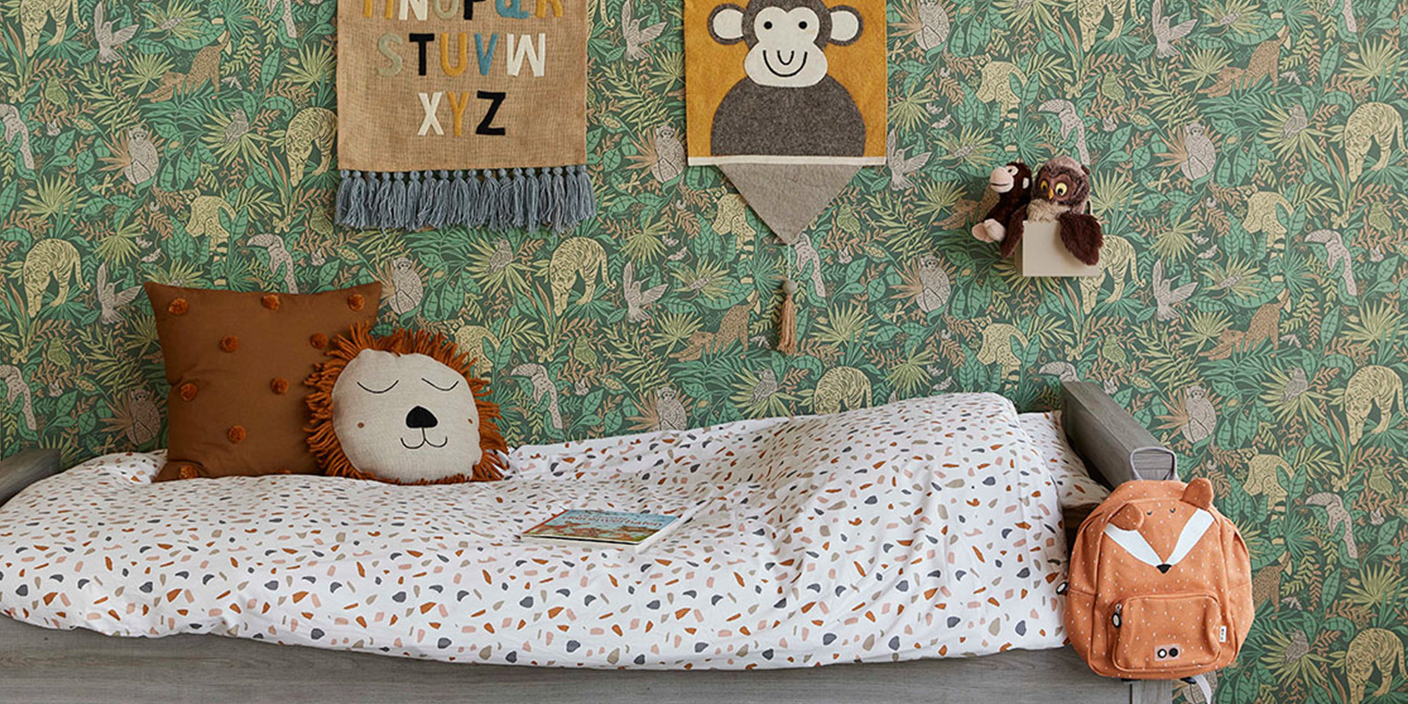 Grüne Kindertapete mit wilden Dschungeltieren, gestaltet hinter dem Bett für eine abenteuerliche Atmosphäre im Kinderzimmer.