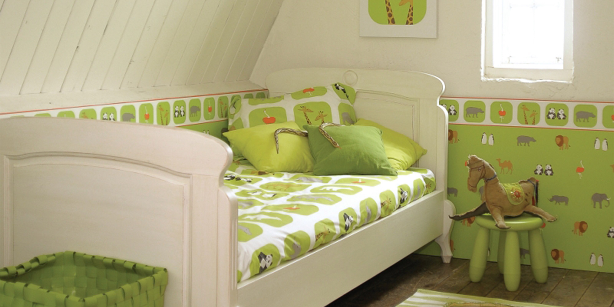 Kinderzimmer mit einer Wandgestaltung aus grüner Tiertapete, ergänzt durch eine passende Bordüre mit Tiermotiven für ein harmonisches Design.